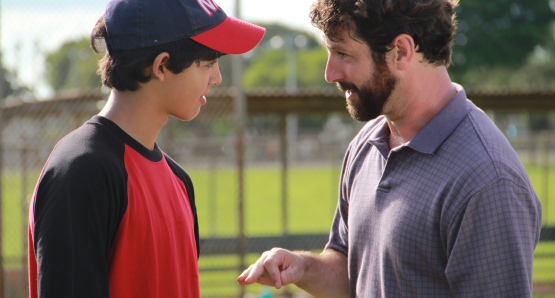 Rabbi Brookstein (Sean McConaghy) and Josh (Luca Oriel) talking on the baseball field.