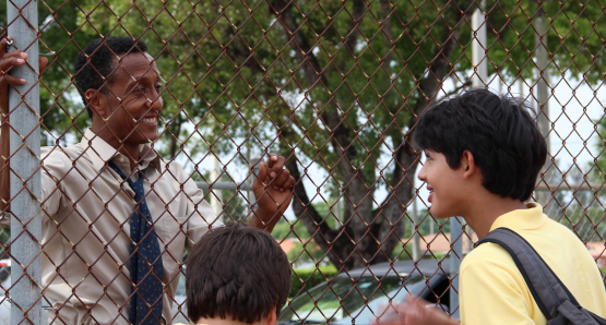 Byrd (Andre Royo) talking to Josh (Luca Oriel) and Tony (Alex Higgins) by the basketball court.